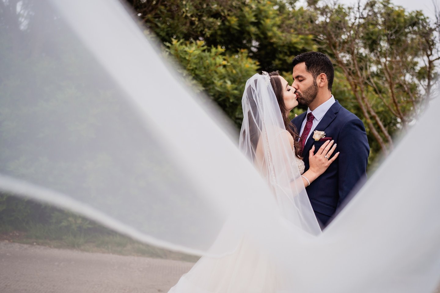 a bride and groom kissing in a veiled veil