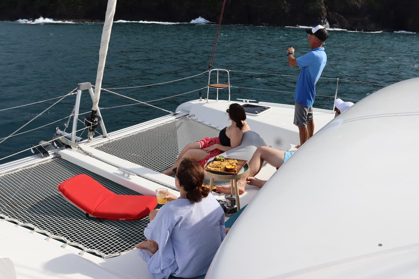 Guests relaxing on deck while crew guides catamaran through Gulf of Papagayo