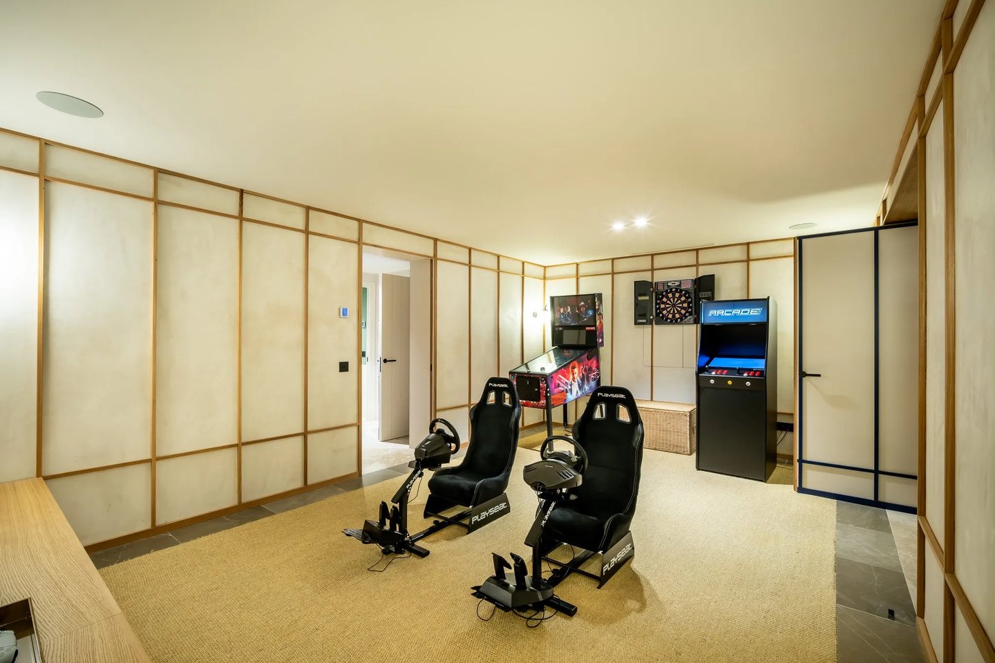 Game room at Villa La Gratitud with racing simulators, arcade machines, and darts