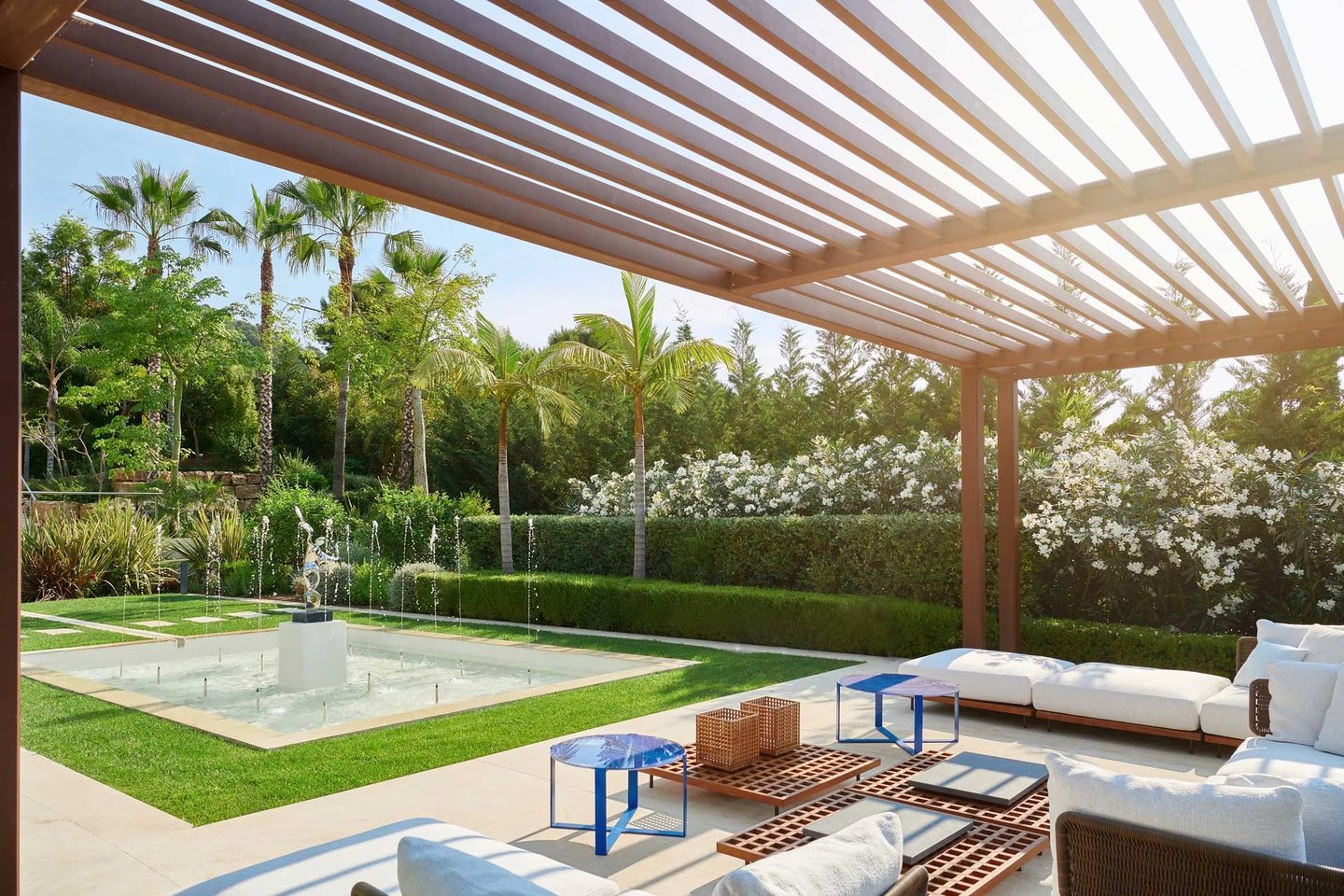 Shaded outdoor seating area overlooking a sculptural water fountain