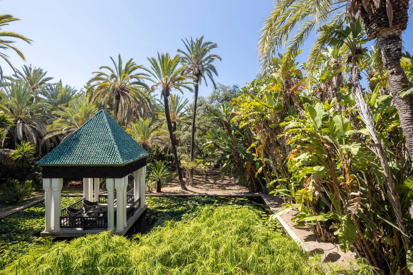 Green-tiled pavilion set within palm-filled water garden
