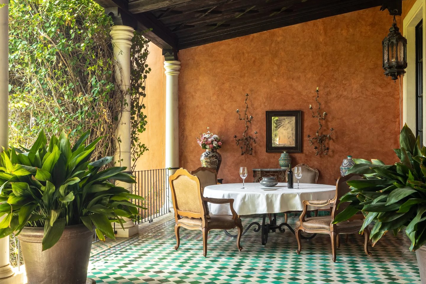 Covered terrace dining area with green mosaic floor and terracotta walls