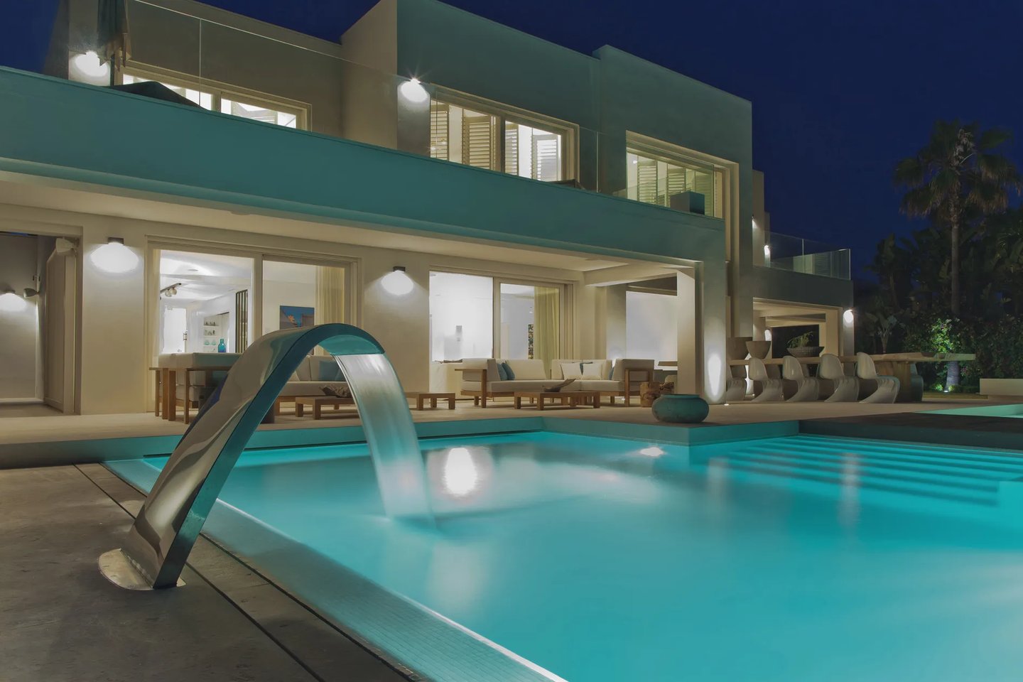 Beachfront villa exterior at night with illuminated pool