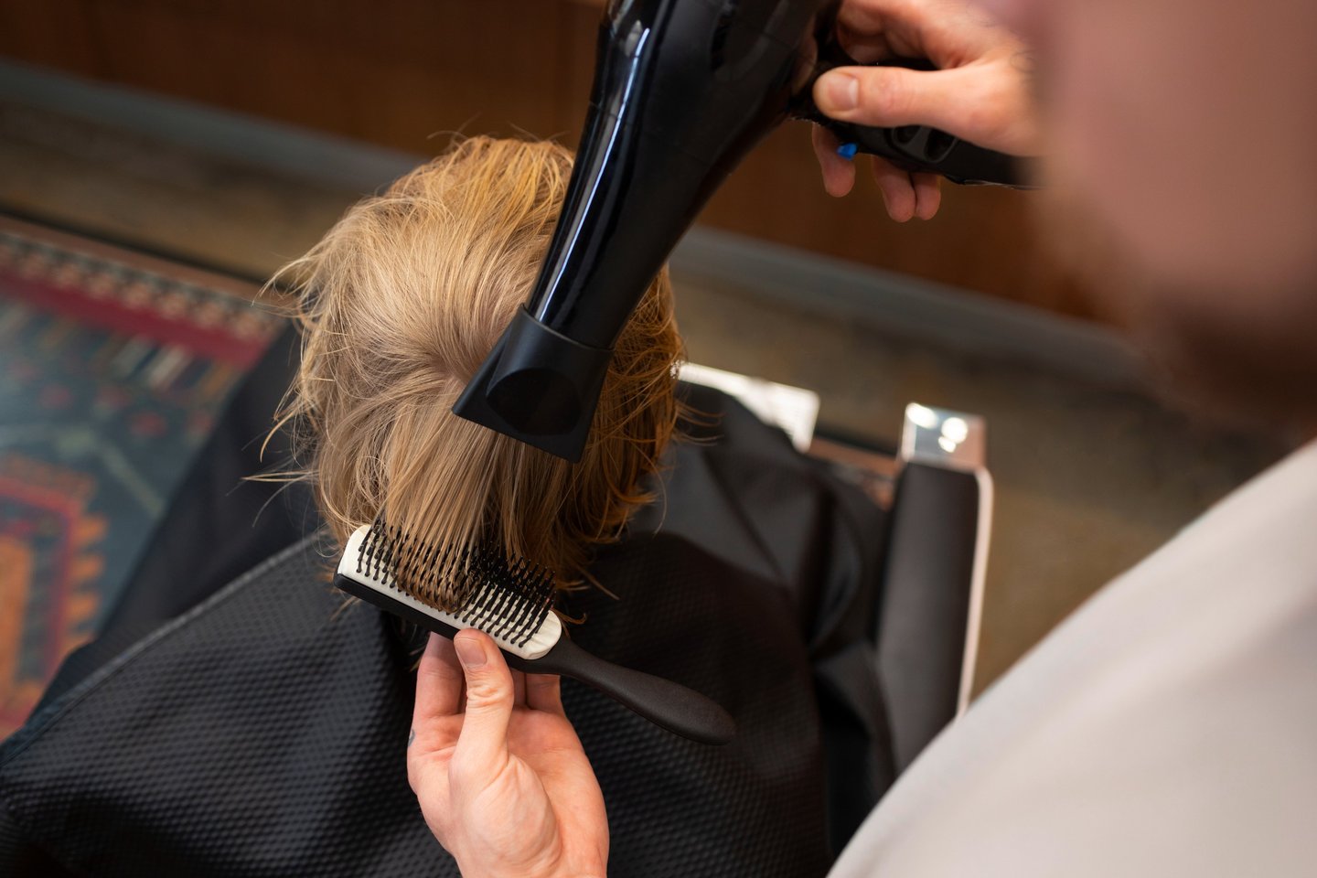 a woman is blow drying her hair in a salon