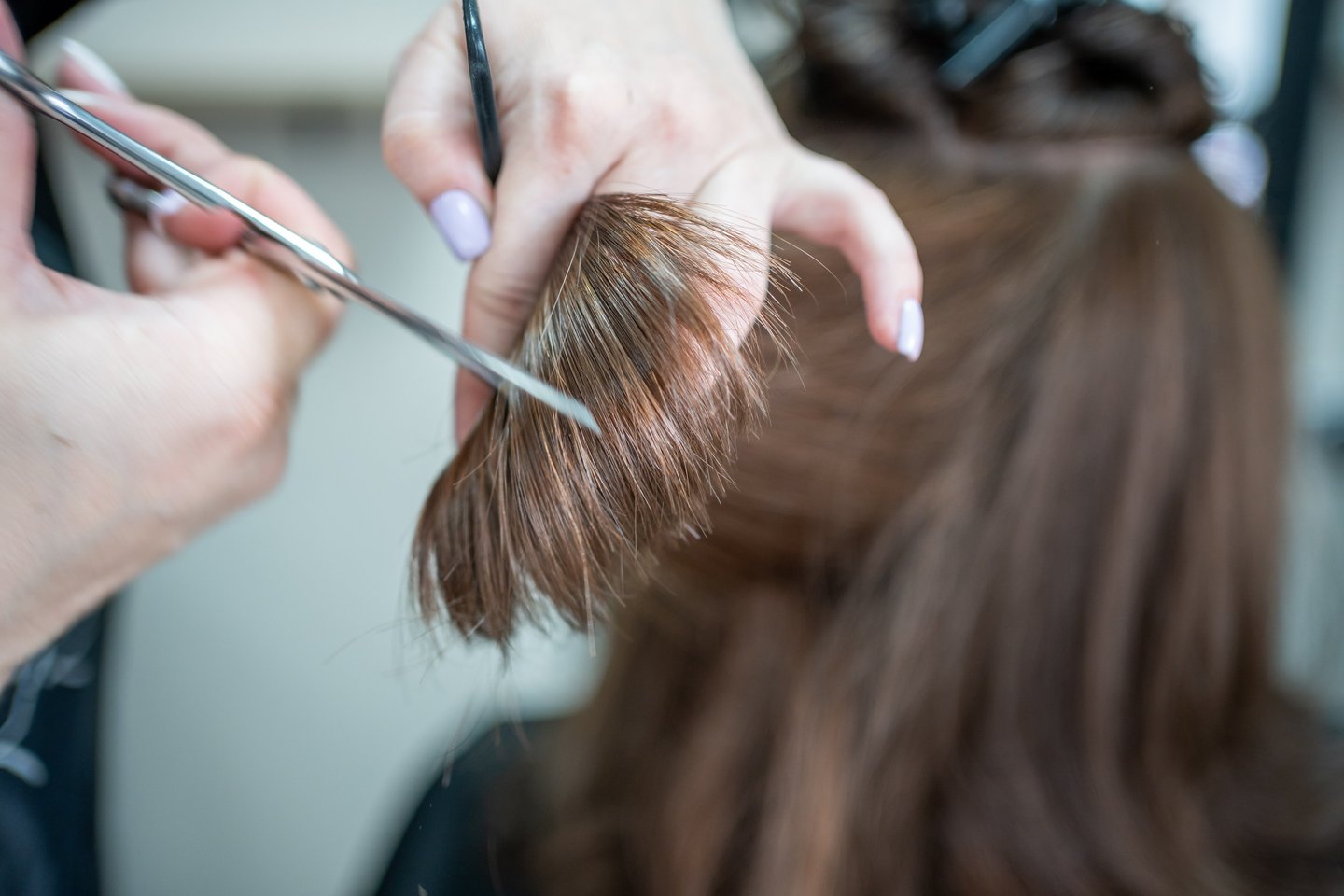 Haircut close-up with scissors and brown hair