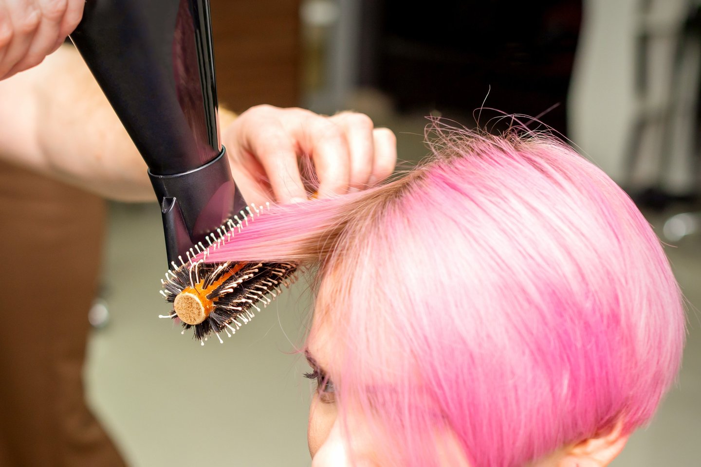 Hair model with vibrant pink full-head color during blow-dry.