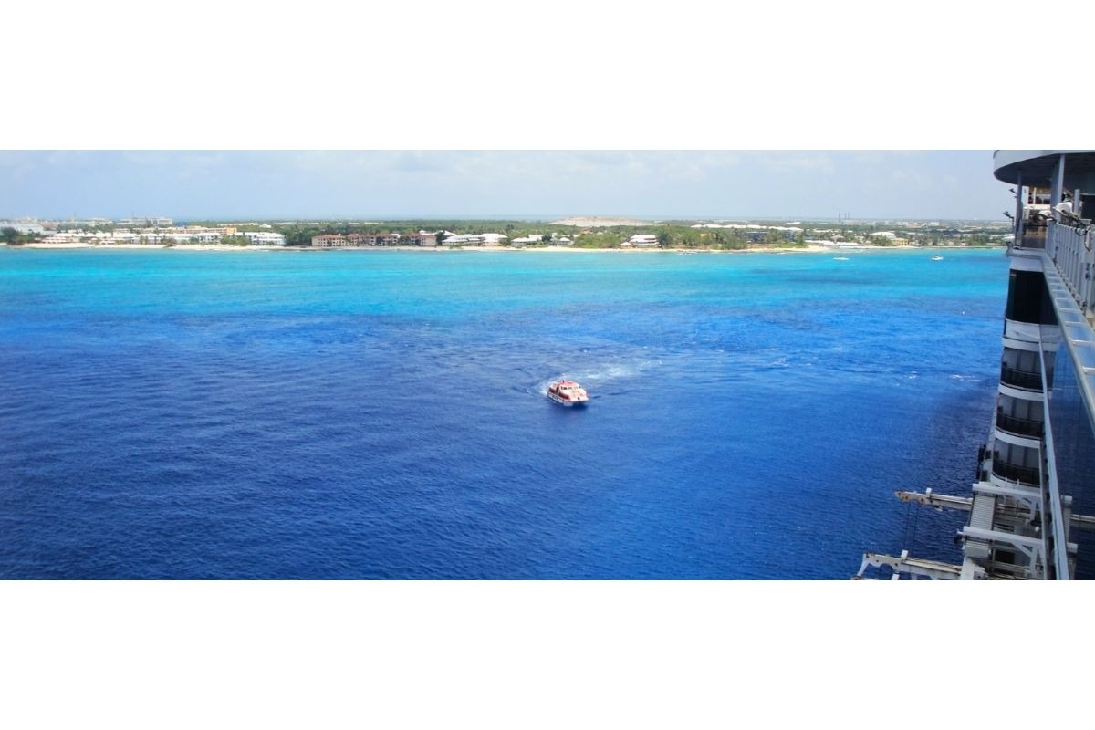 Navio de cruzeiro chegando a George Town, Grand Cayman, com o mar azul-turquesa cristalino ao fundo.