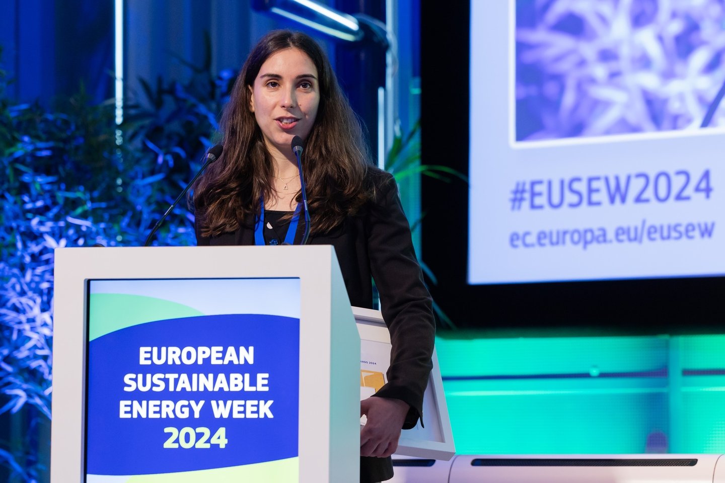 a woman in a black jacket speaking at the european sistainable energy week 2024