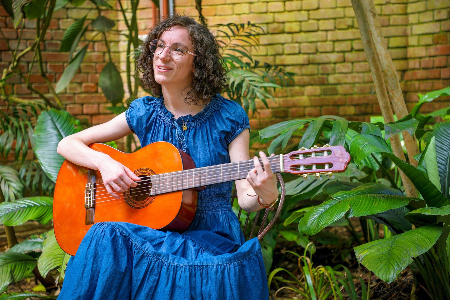 chanteuse guitariste en robe bleue chantant dans une serre