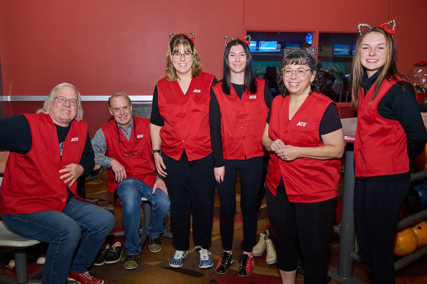 a group of people with red vests standing next to a bowling lane