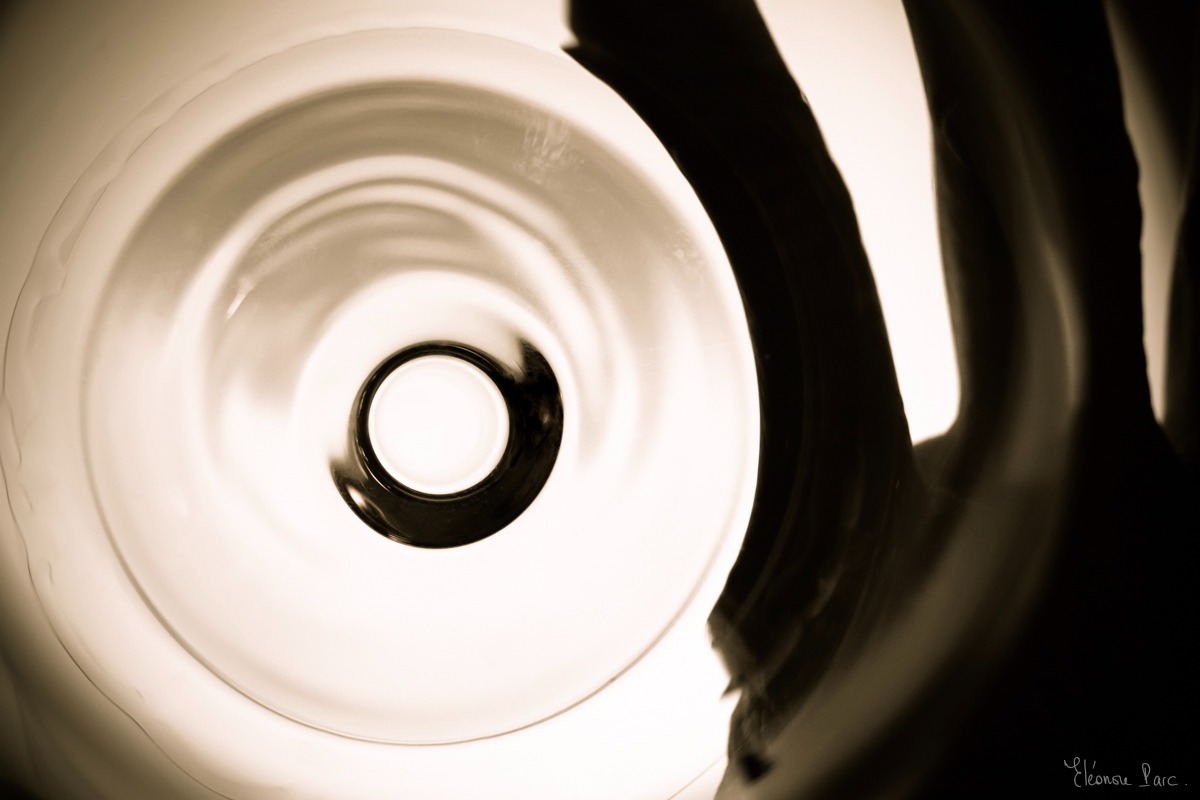 Cercle central d’un verre vu en plongée, ombre de la main sur la droite..