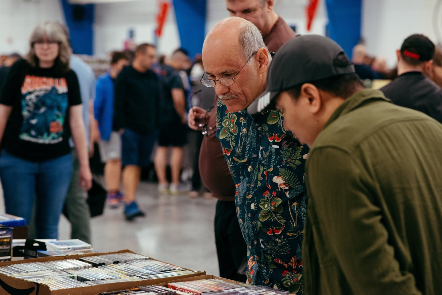 Two men look engaged and curious as they browse a selection of video games for sale.
