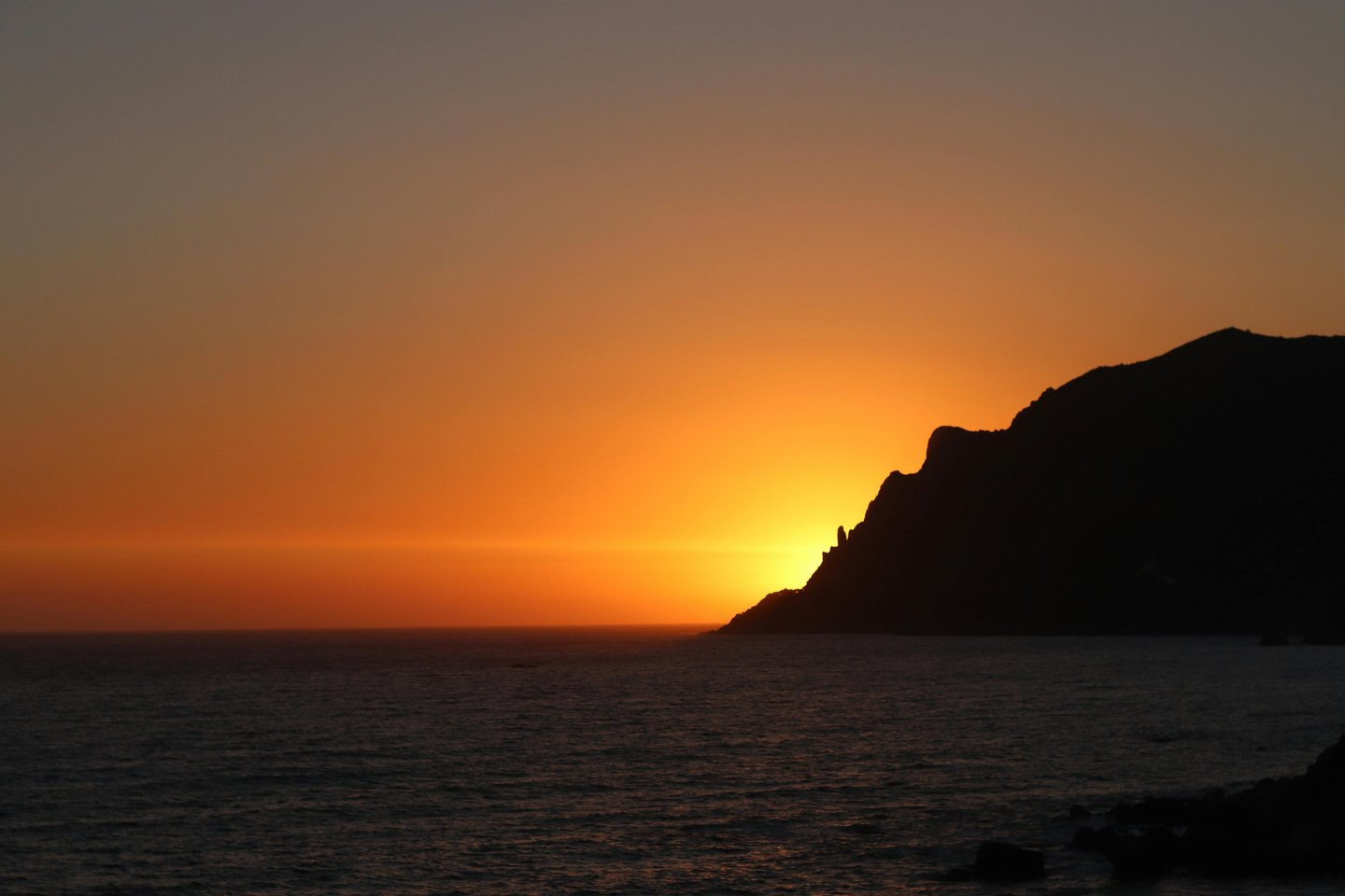 a sunset over the ocean with a boat in the water