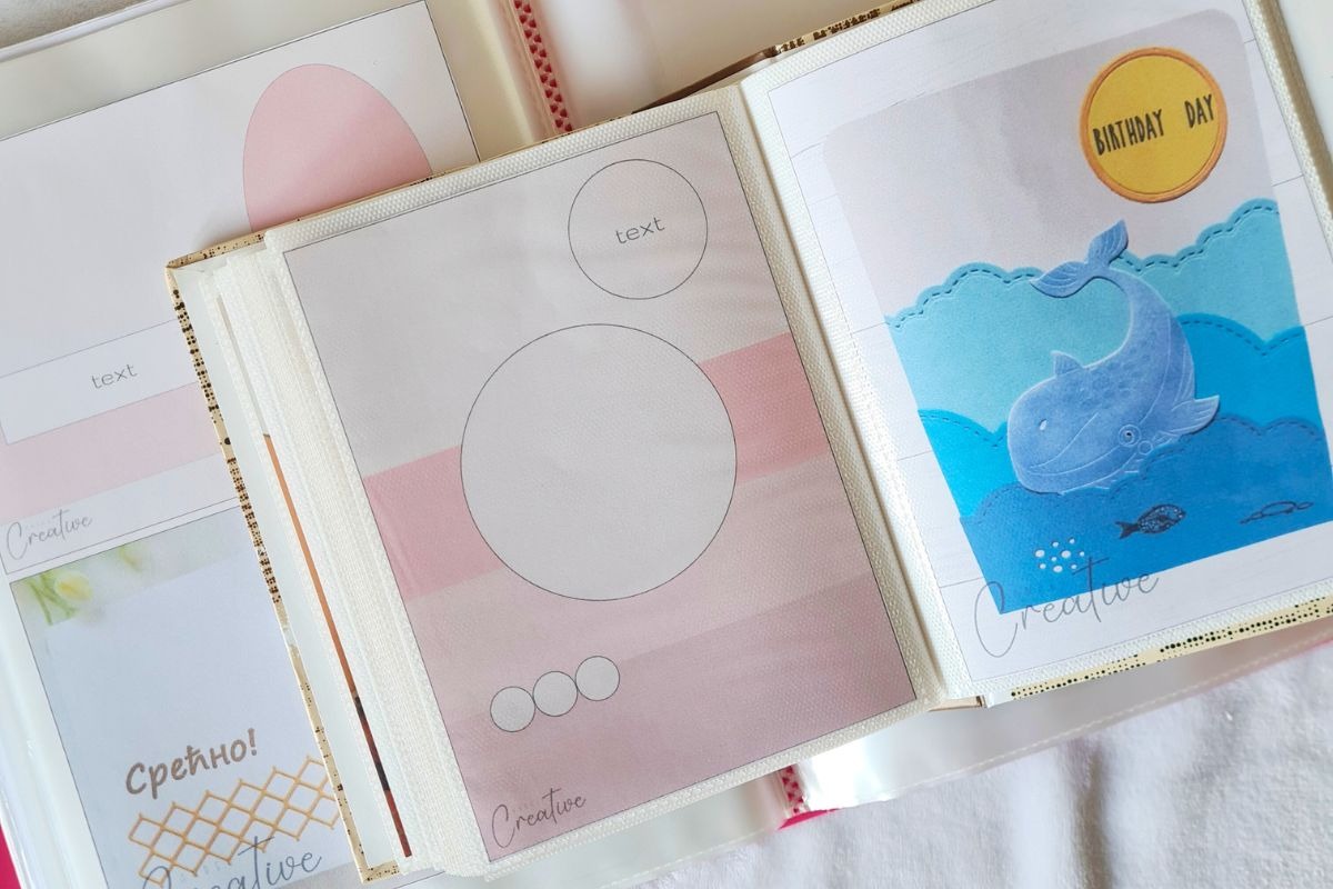 Open photo album with pastel-themed card making sketches. Left page has pink circles for text; right
