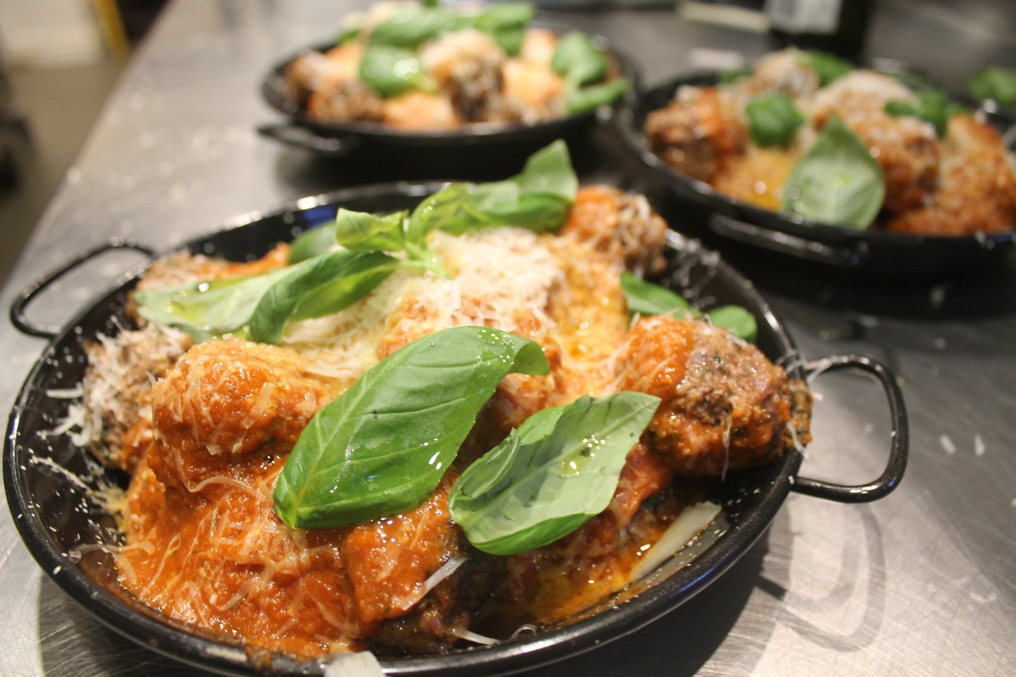 a pan of meatballs with basil sauce