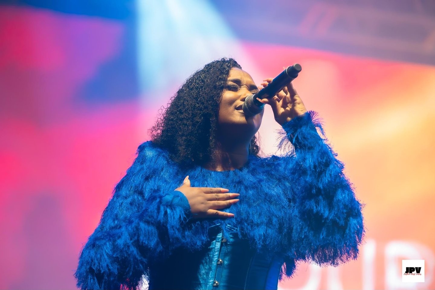 Fanny J portant une combinaison bleue roi effet plume signée Anais Ricard