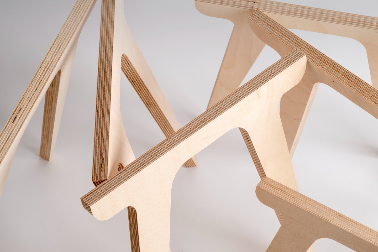 Close-up of interlocking birch plywood furniture legs showing layered wood grain edges.