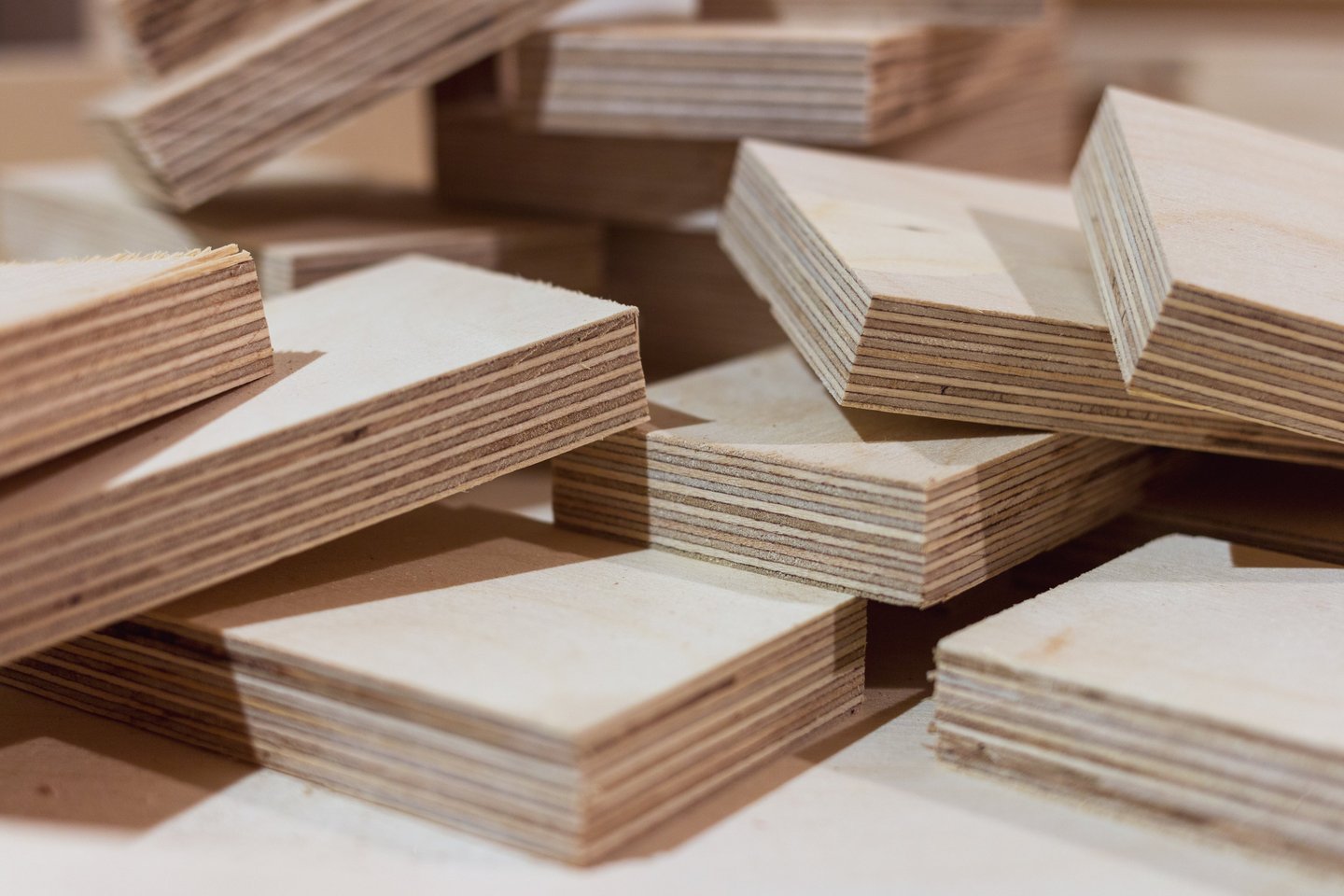 Stacks of cut birch plywood boards showing multi-layered wood grain for construction.