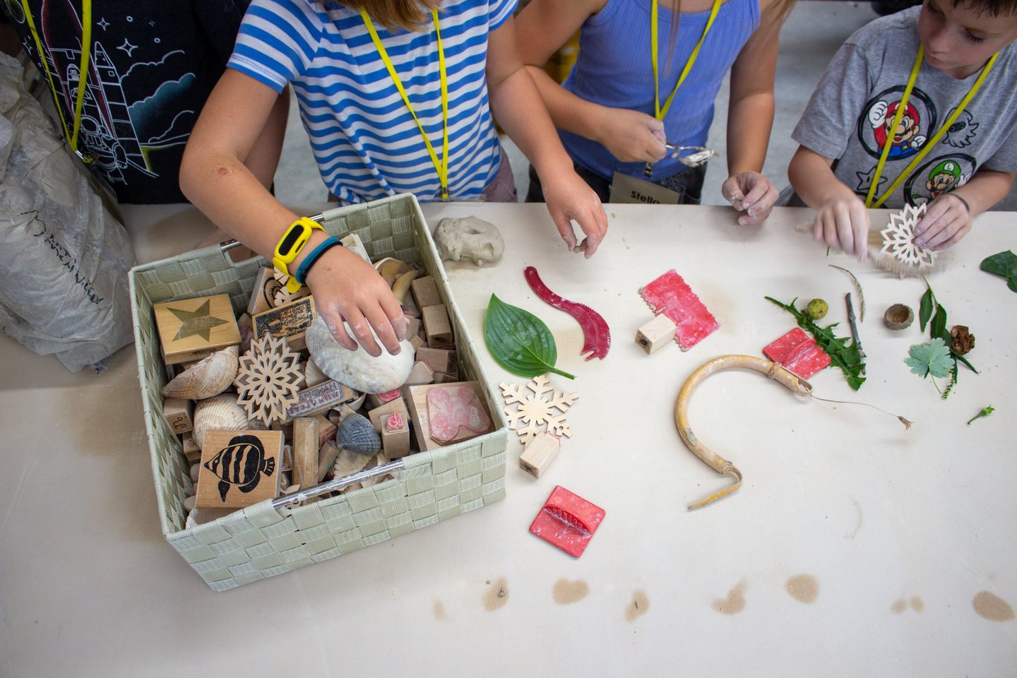 Children's hands reaching into a bin of stamps and supplies.