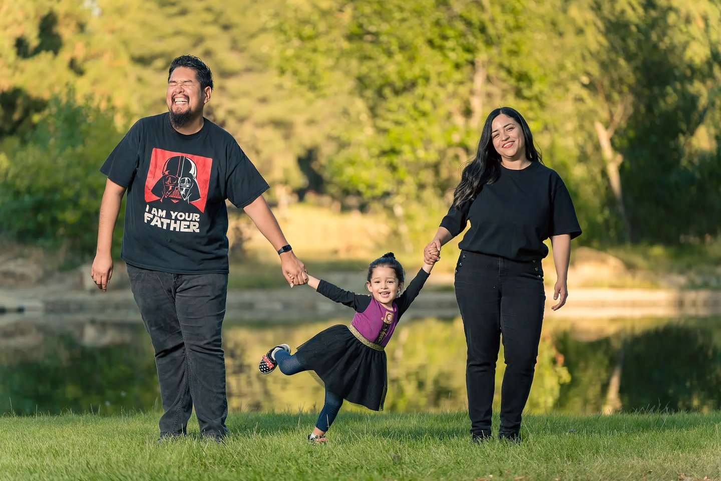 family photoshoot of a man and woman holding hands and holding kid by her hands