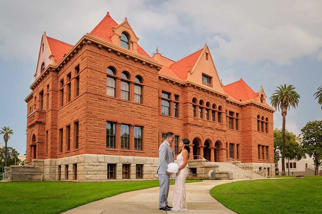 A bride and groom standing in front of the Old Orange County Courthouse
