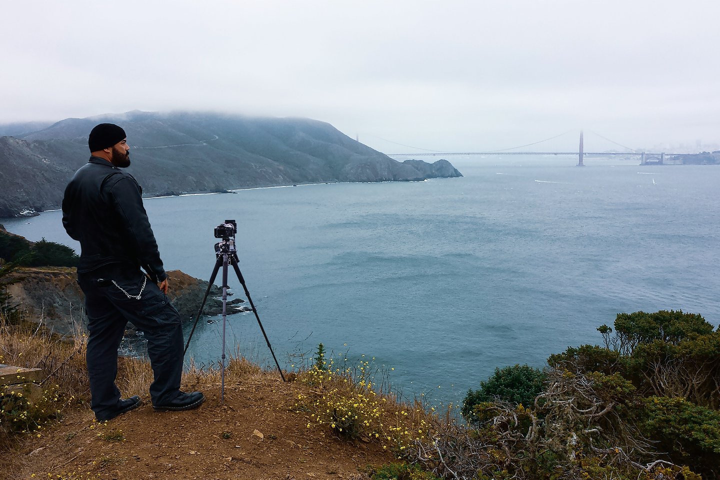 a man standing on a hill overlooking a bridge