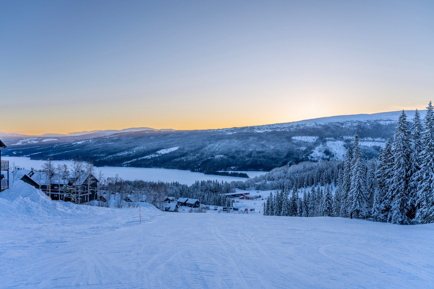 view of a snowy landscape on a piste during sunset