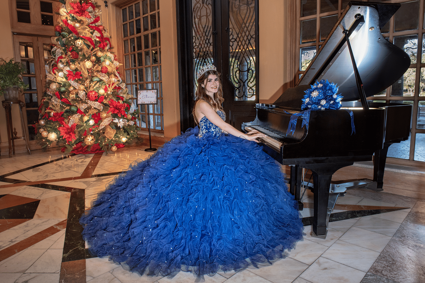 a young girl in a blue dress sitting at a piano posing for photographer