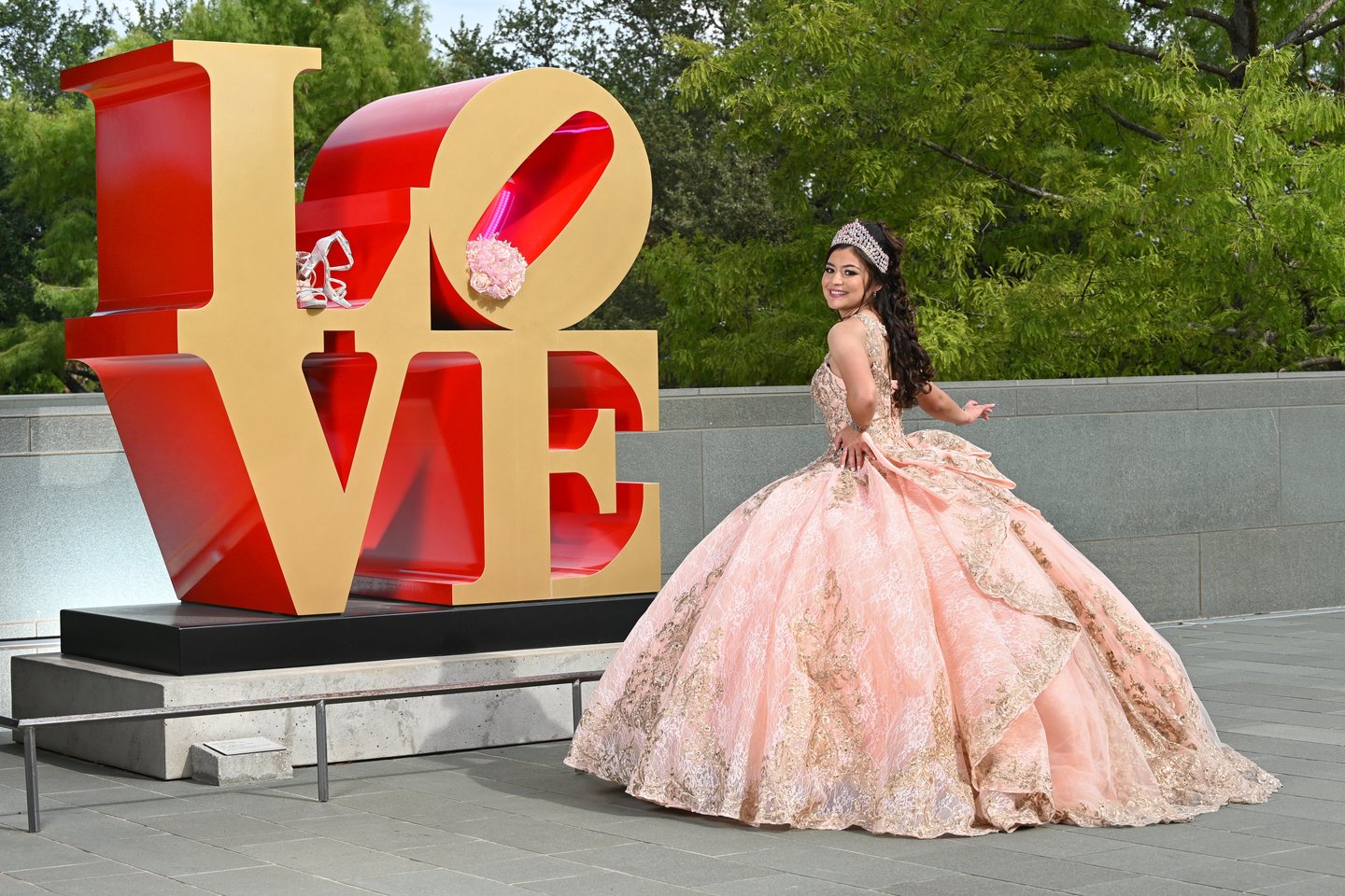 a woman in a pink dress standing in front of a love sign