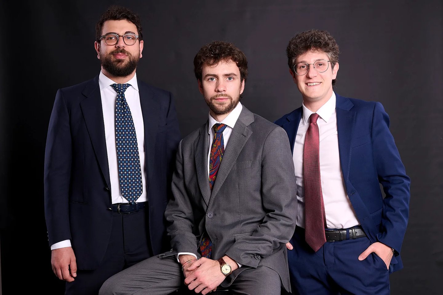 Three lawyers wearing formal suits and ties posing for a corporate group portrait.