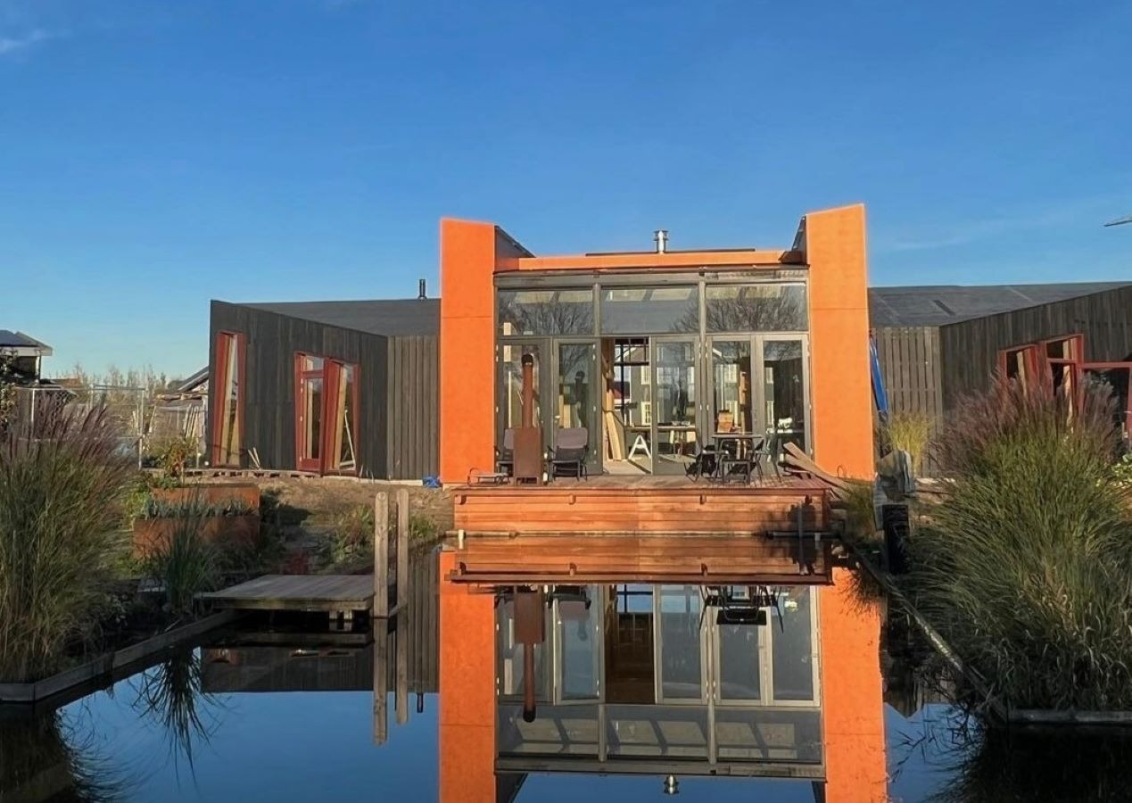 Fachada da casa sustentável prefabricada em CLT com a piscina natural no primeiro plano