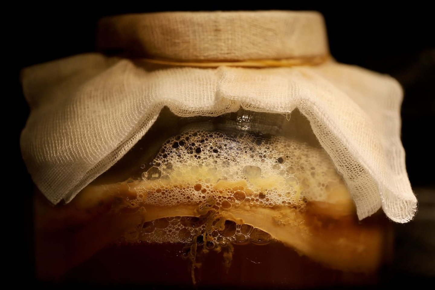 Fermentación de kombucha casera en un frasco de vidrio con SCOBY y cubierta de tela.