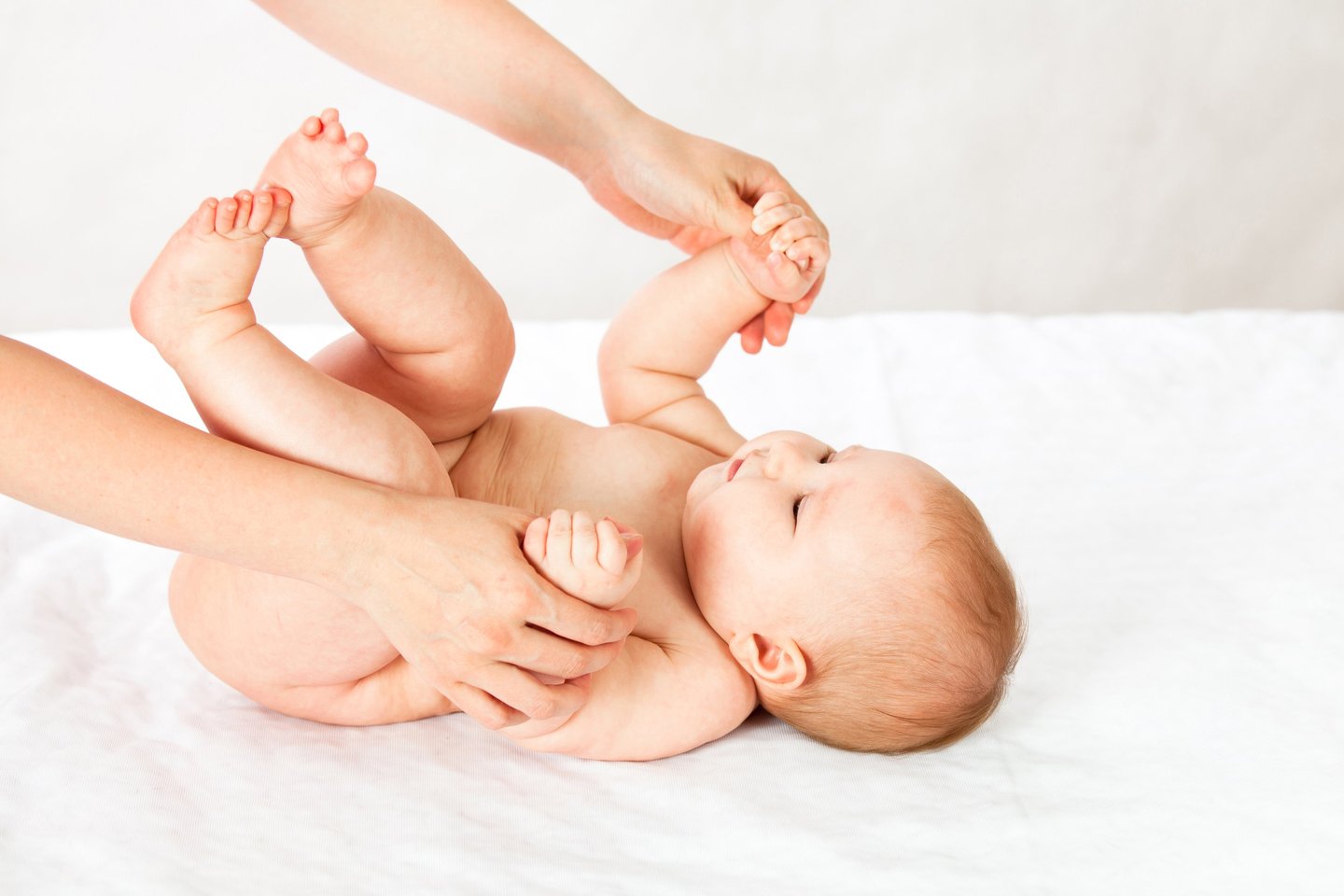 a baby is laying on a bed with a woman's hands