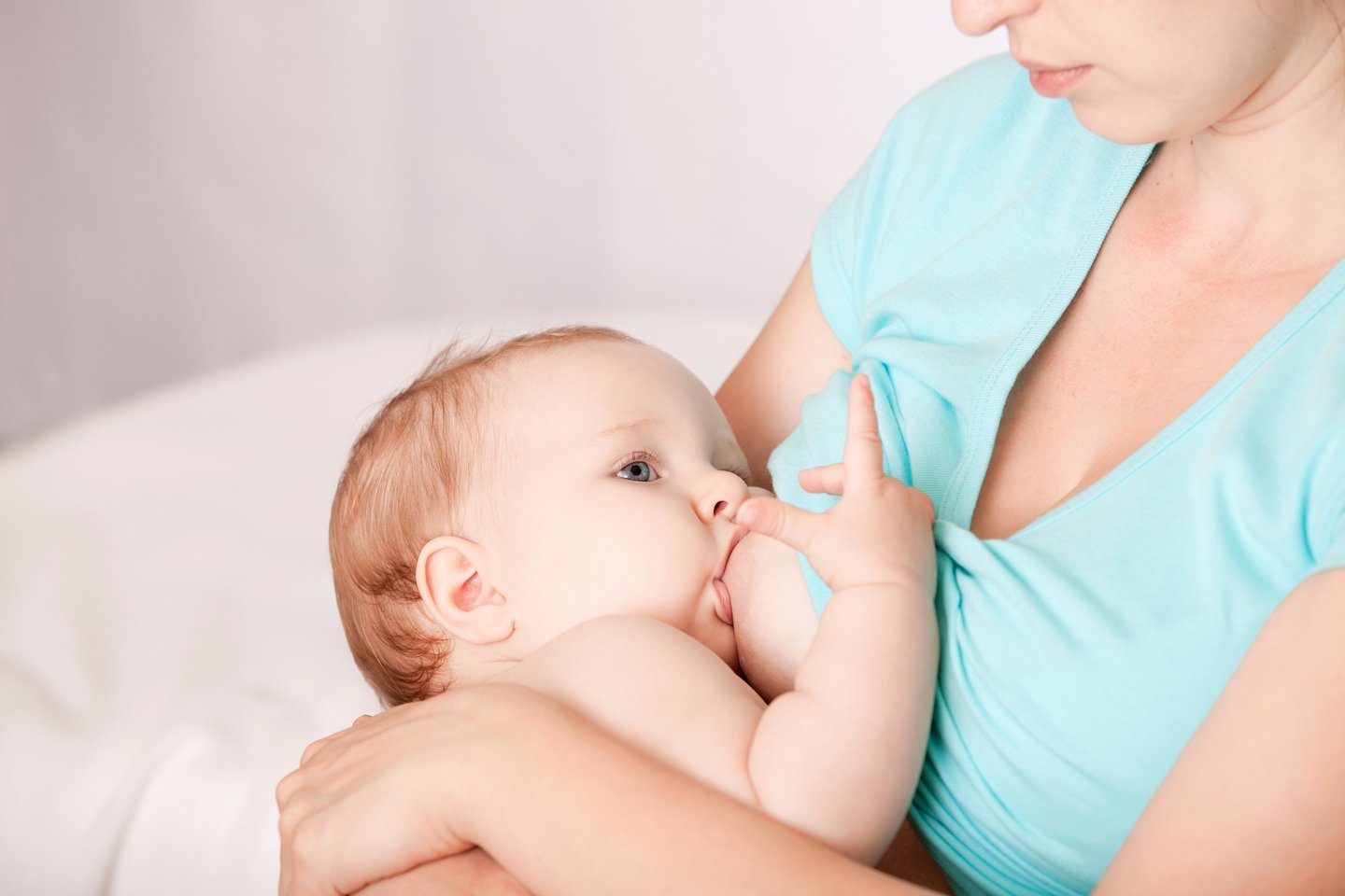 a woman breastfeeding a baby in a blue dress