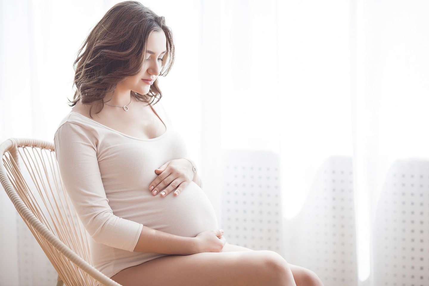 a pregnant woman sitting in a chair holding her belly