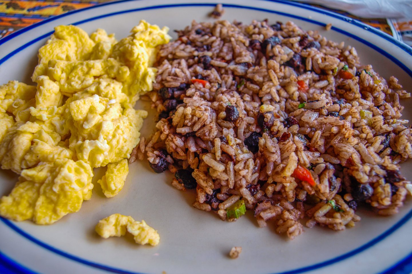 A plate of traditional Costa Rican Gallo Pinto served with fluffy scrambled eggs for breakfast.