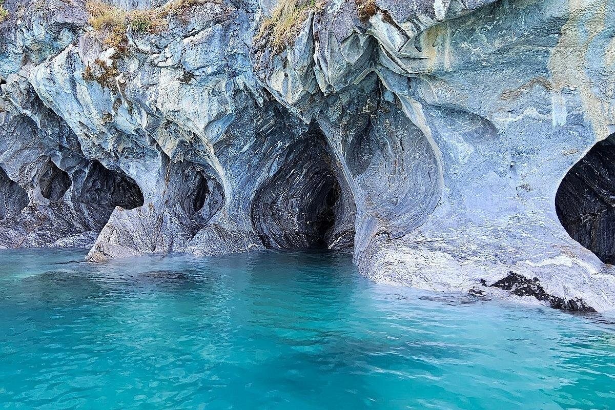The Marble Caves of Patagonia with sculpted blue rock formations over clear turquoise water in Chile.