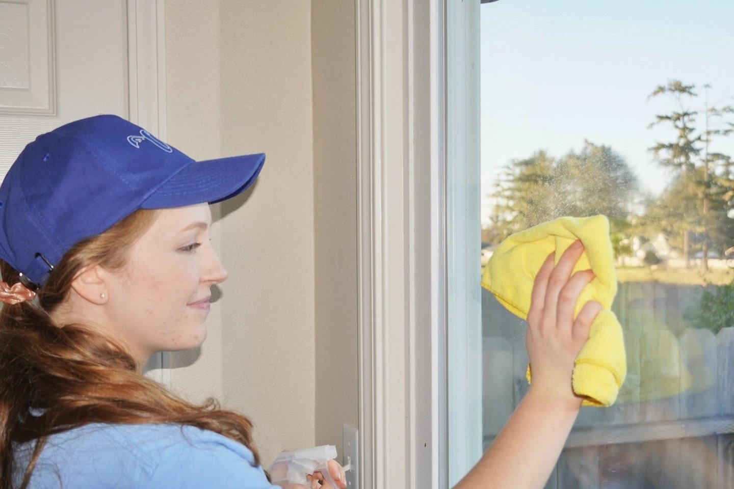 Lady cleaner from Chez Cleaning Services cleaning a glass door of a house with a rag