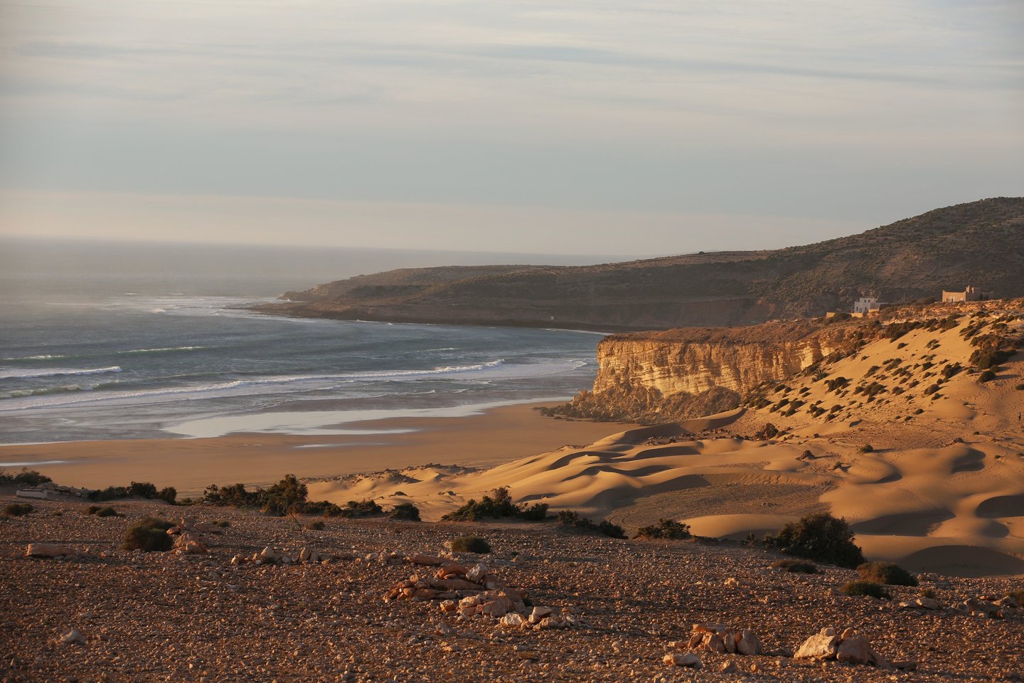 Plage magnifique au coucher de soleil avec l'océan, des dunes de sable et des falaises