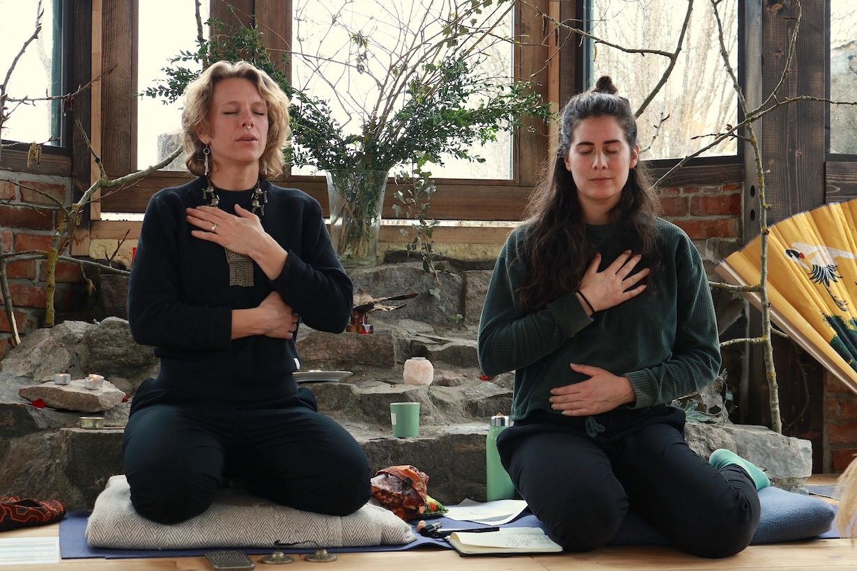 two women sitting on a mat with umbrellas
