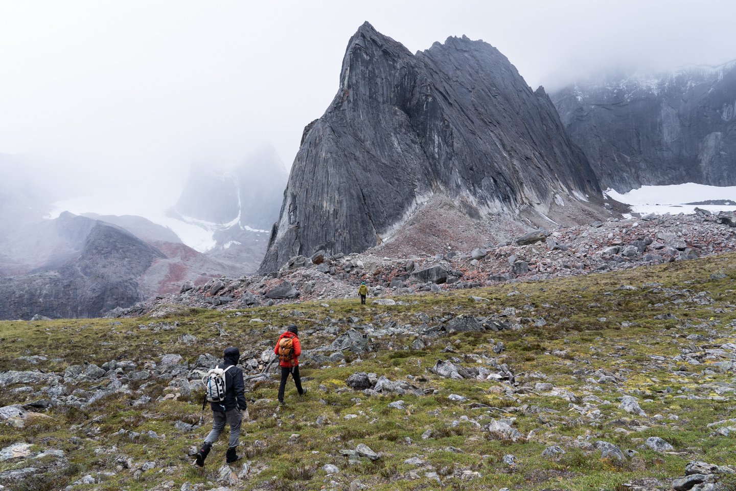 Climbers approach granite spires rising above tundra in the Arrigetch Peaks, Brooks Range, Alaska