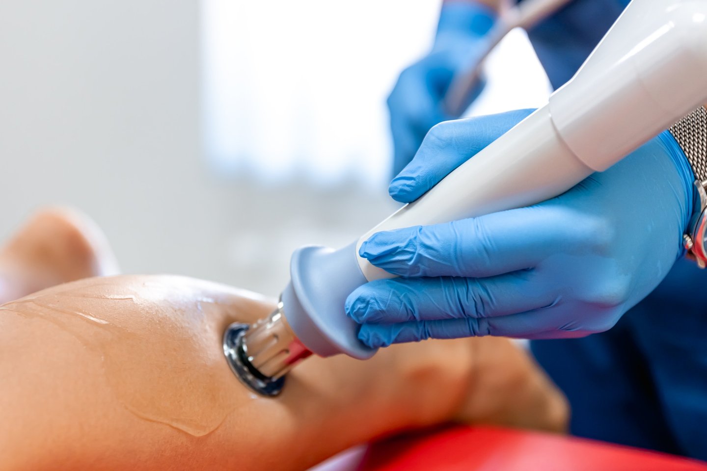 Professional phlebologist applying shockwave therapy on a patient's leg 