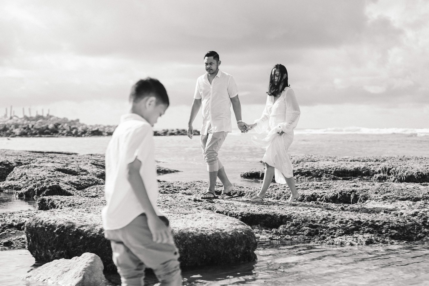 Ayunda family walking together across the rocks at Melasti Beach during sunset family photography in Bali.