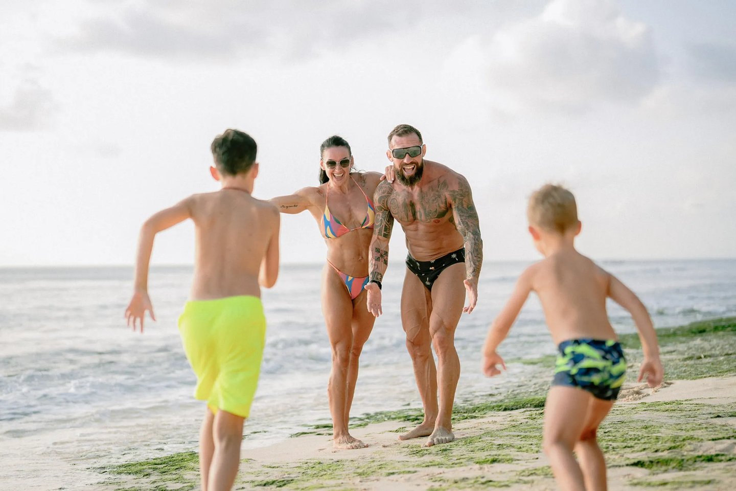 Children running toward their parents during a playful family photography session at Dreamland Beach Bali.