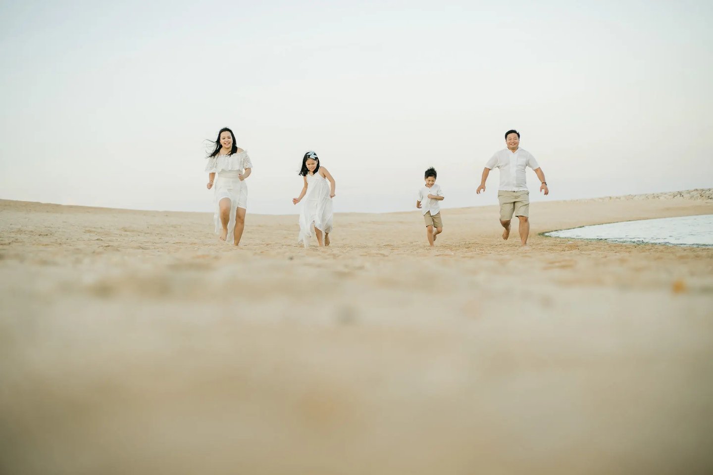 Family running together along the beach at The Apurva Kempinski Bali