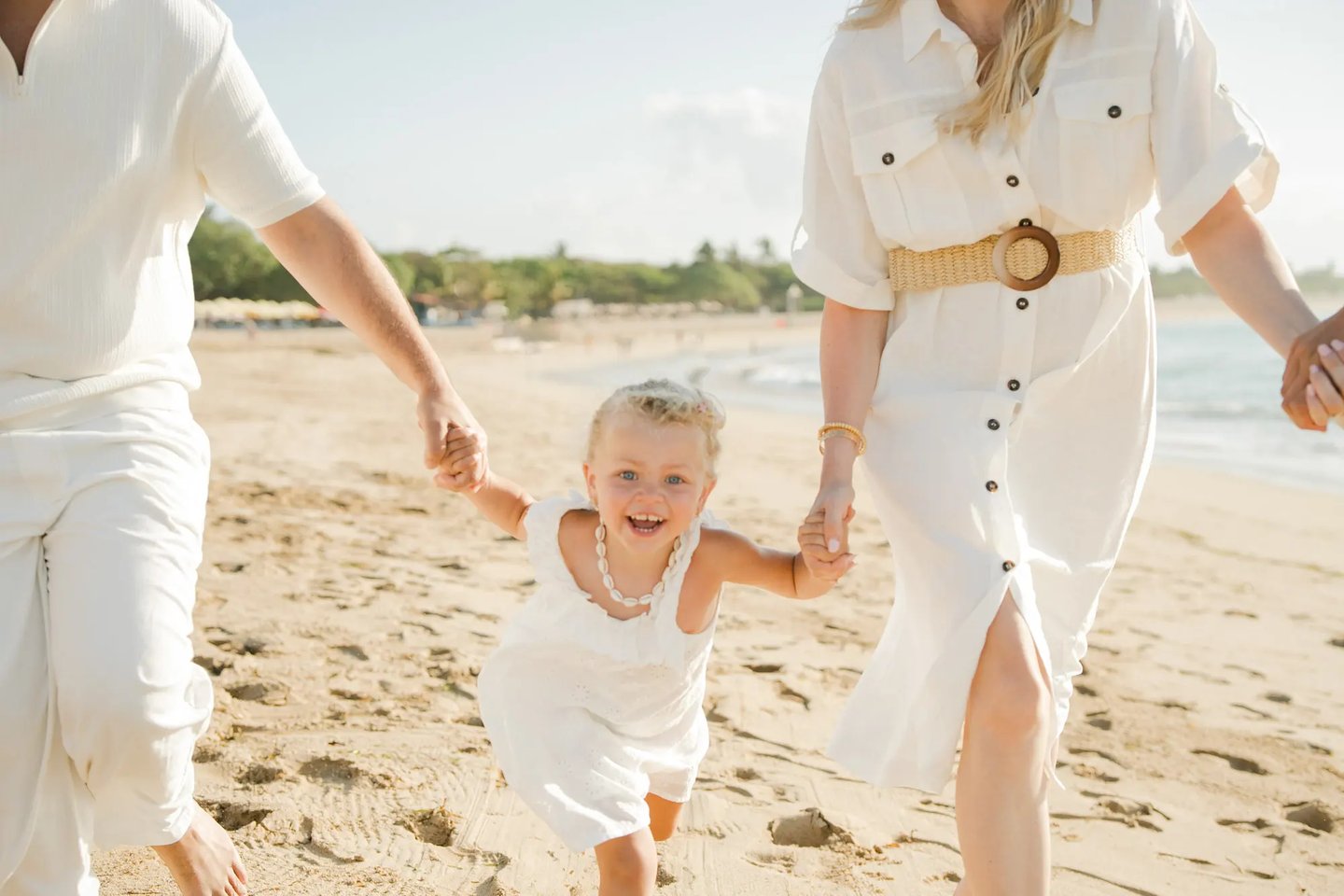 Young child running happily along the beach during a family photography session at Ayodya Resort Bali