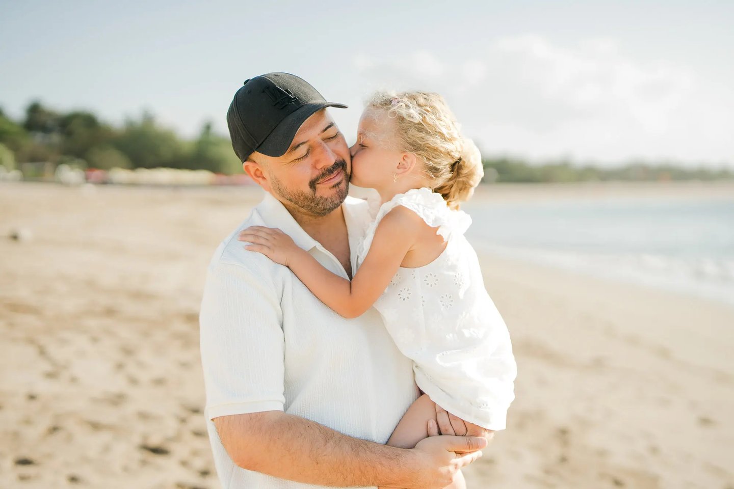Father holding his daughter during a sunset family photography session at Ayodya Resort Bali in Nusa Dua