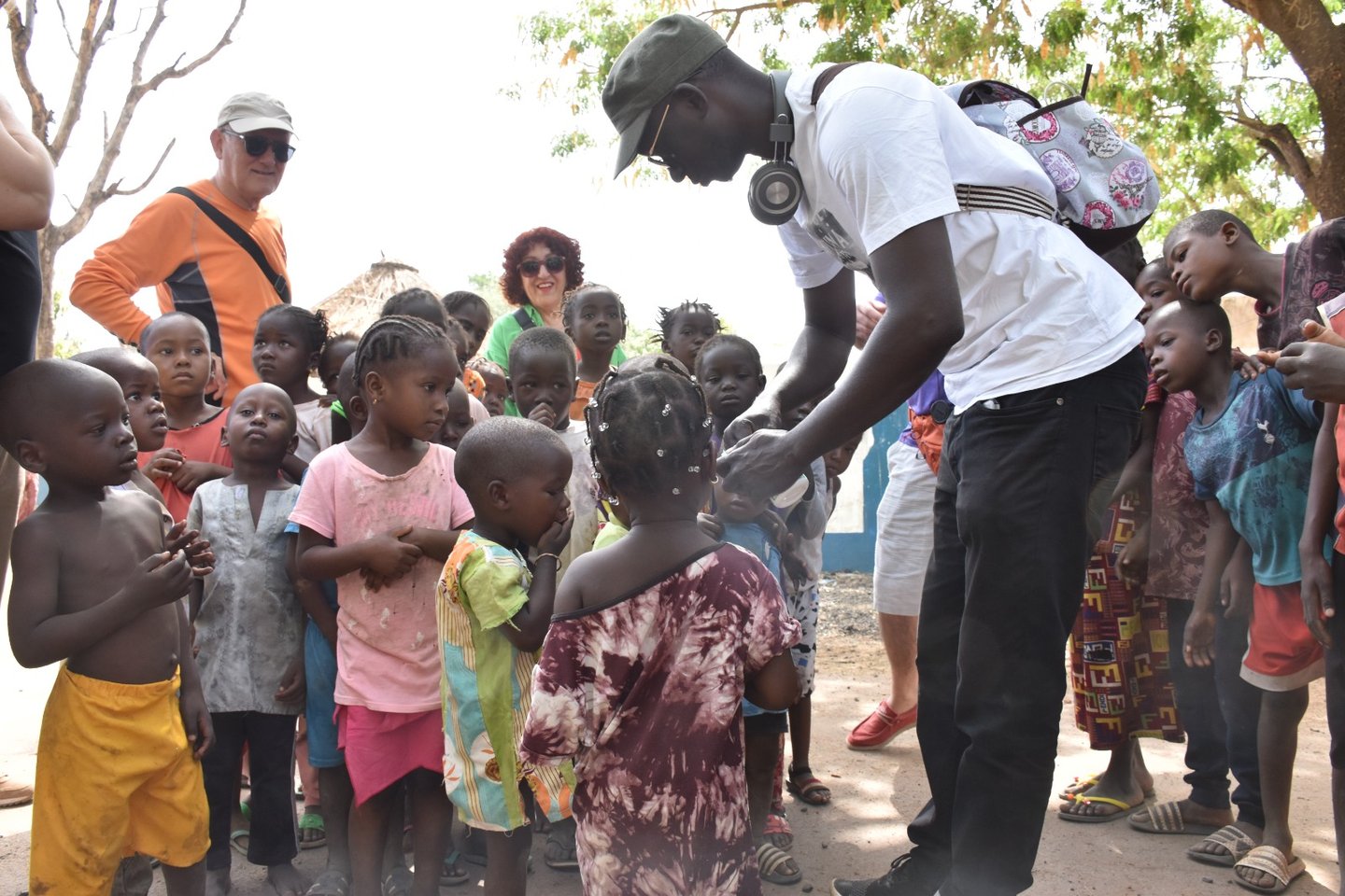 Dahomey African Tours Guide leading Tourists and giving gifts to Children in Senegal