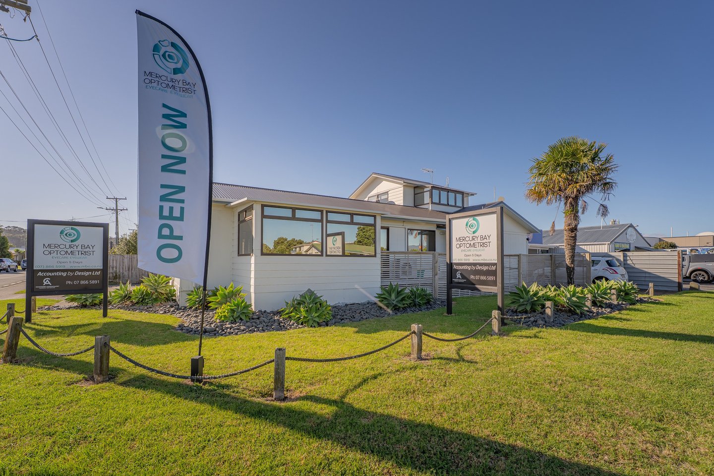 MBO building - white with reflective windows and blue sky with signs Open Now