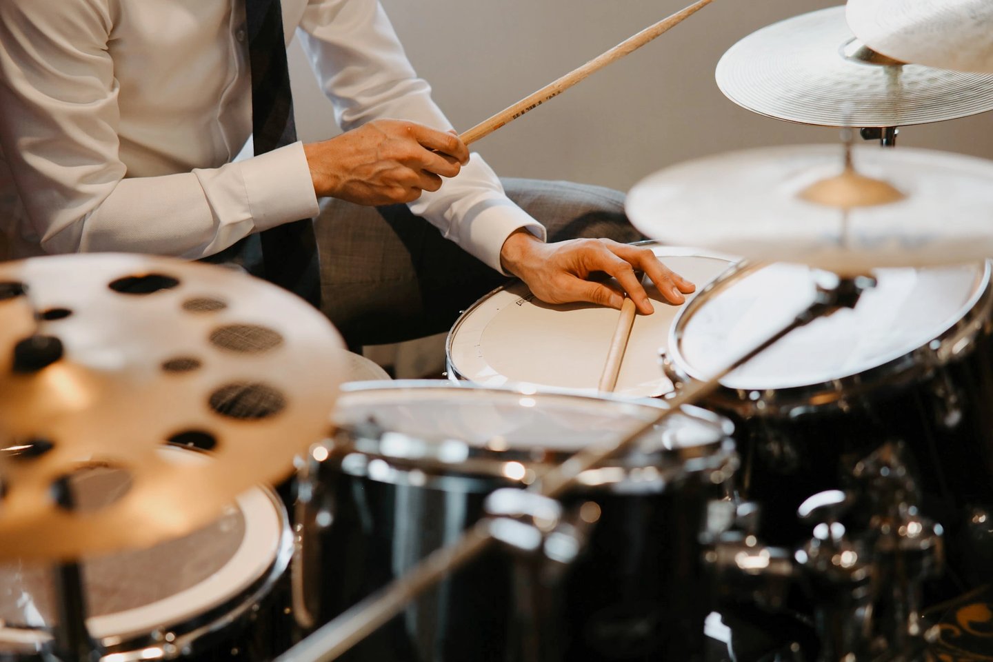 a man in a tie and tie shirt playing drums